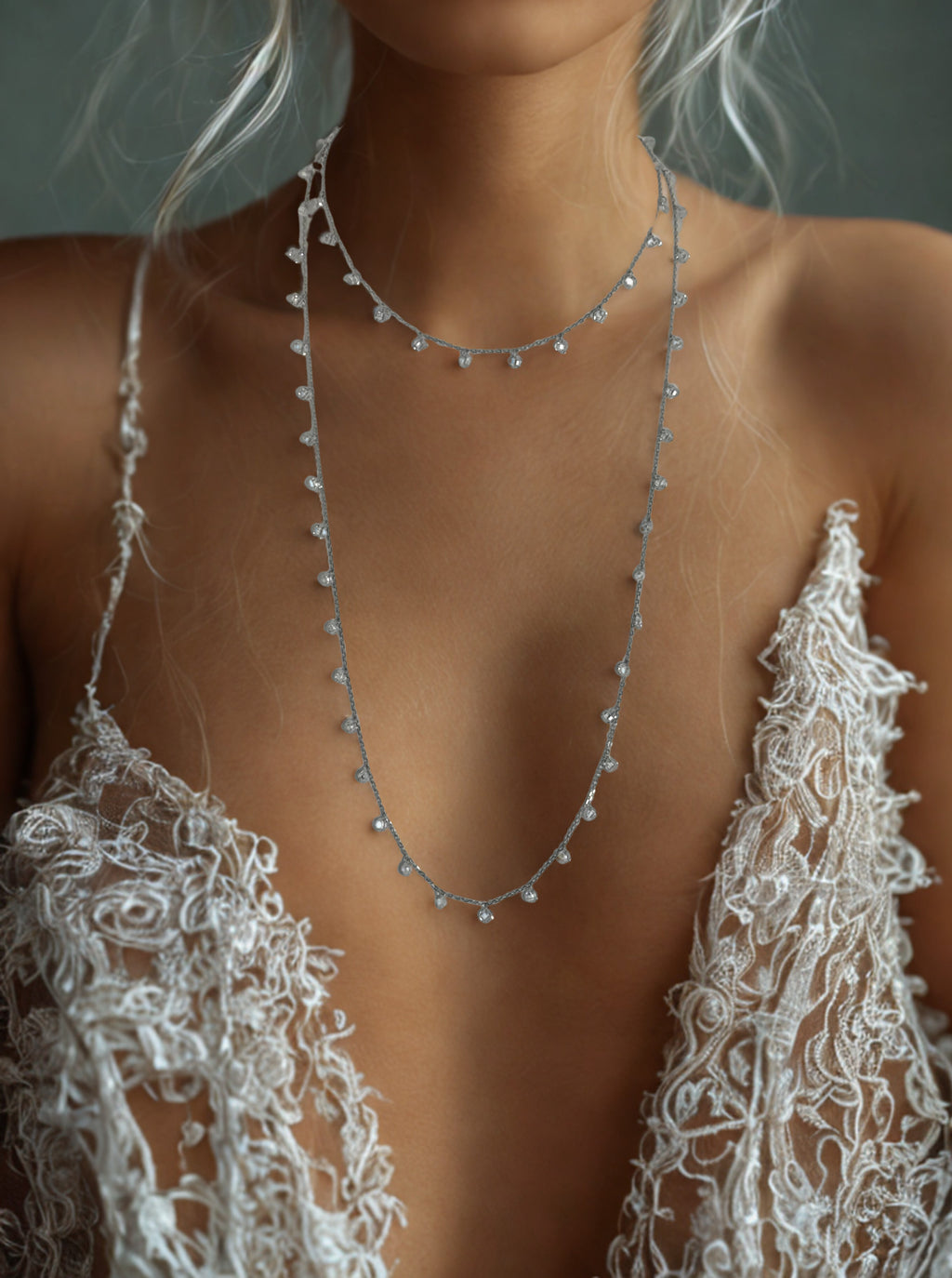 Close-up of a necklace worn by a person in a lace garment.