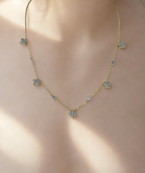 Gold necklace with diamond-like stones on a neutral background