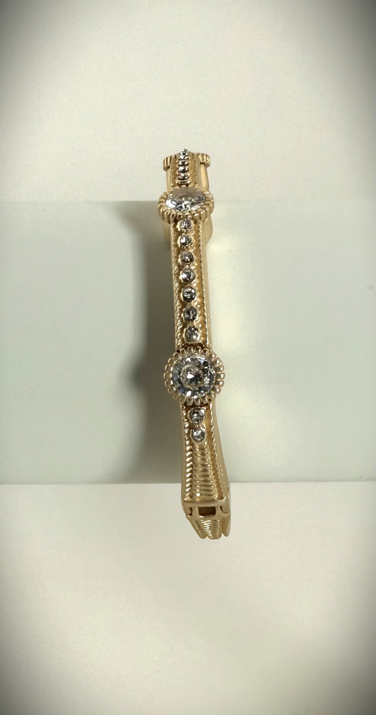 Gold bracelet with decorative elements on a light background