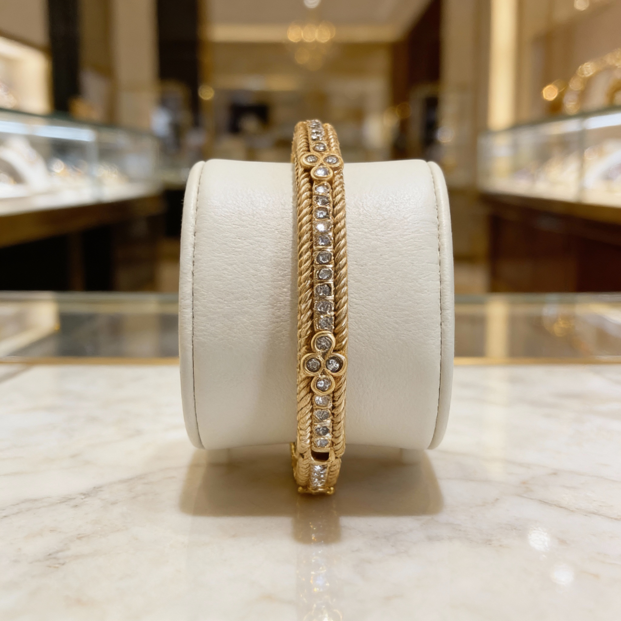 Ornate gold and diamond stackable bracelet displayed on a white leather cuff.