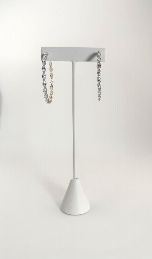 Two-tone silver and gold diamond hoop earrings on a white jewelry stand