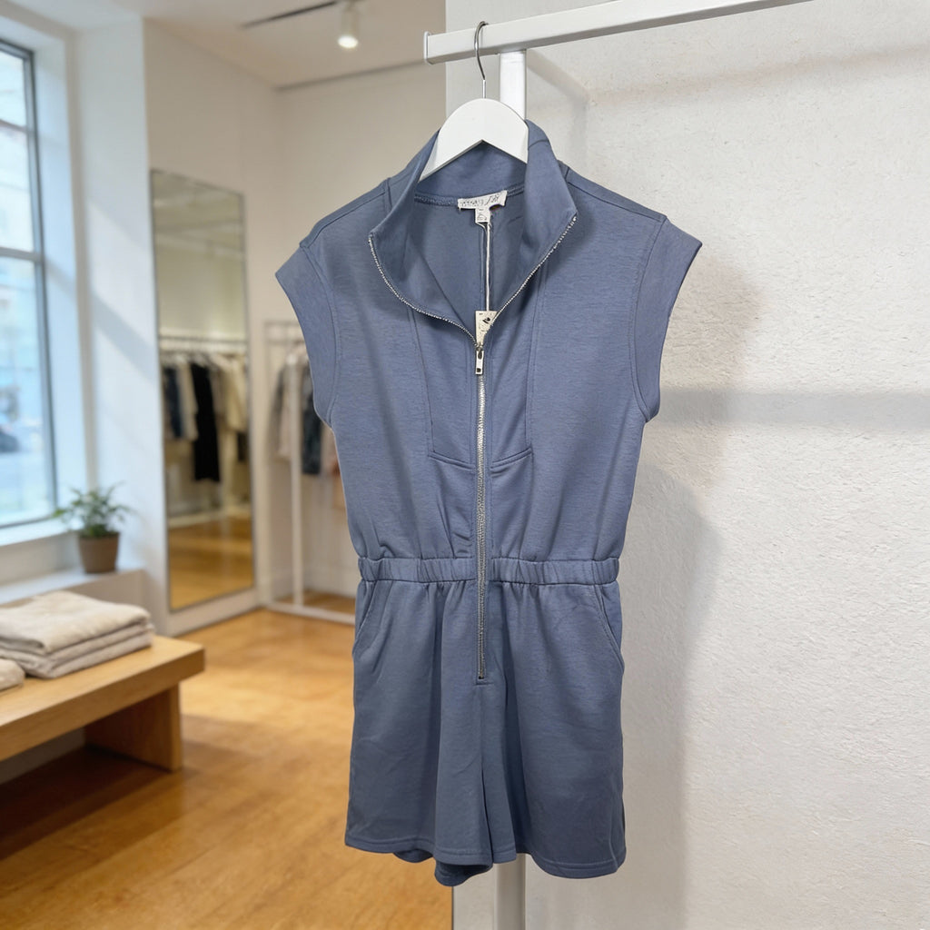 Front view of dusty blue sleeveless half-zip romper with elastic waist and soft knit fabric