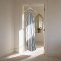Striped dress hanging in a sunlit room with a mirror in the background