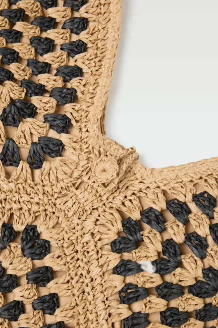 Close-up of a beige and black woven bag with a white background