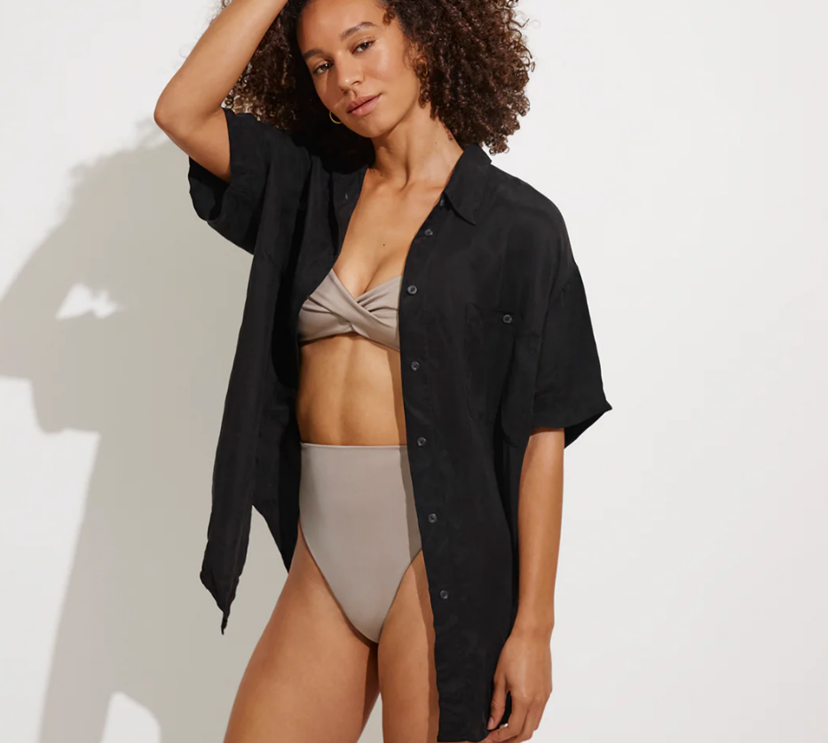 Woman wearing a black shirt over a beige bikini on a white background