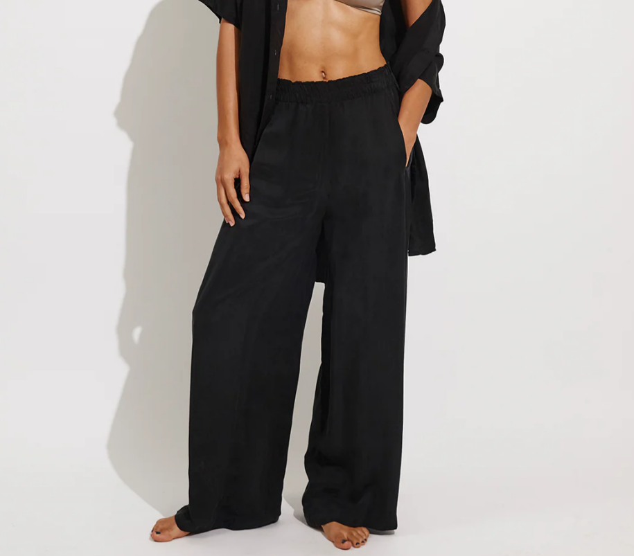 Person wearing black wide-leg pants and a black top on a white background