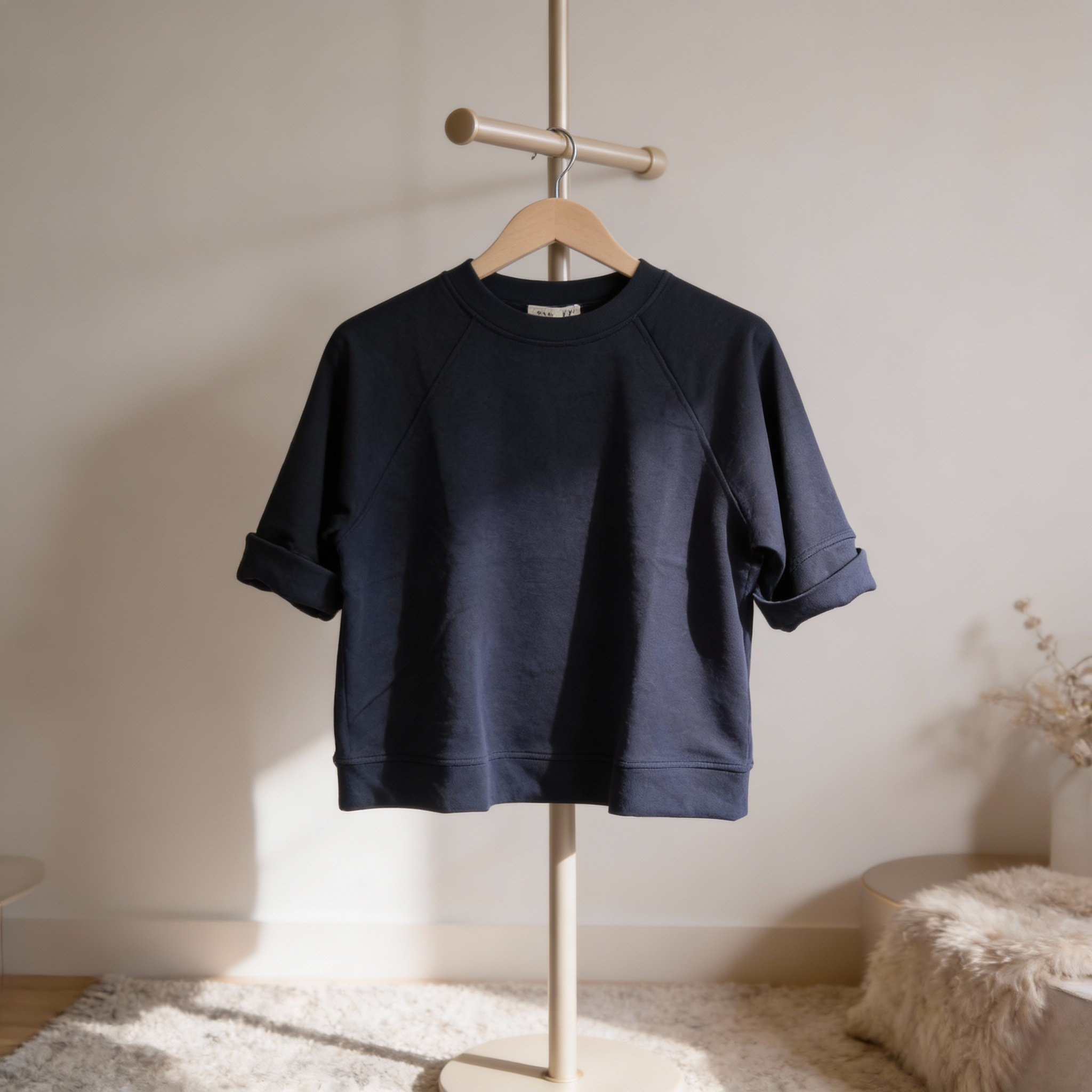 Navy blue scuba knit shirt on a hanger against a neutral wall.