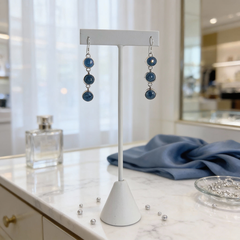 Sterling silver dangle earrings with blue aventurine stones displayed on a white jewelry stand.