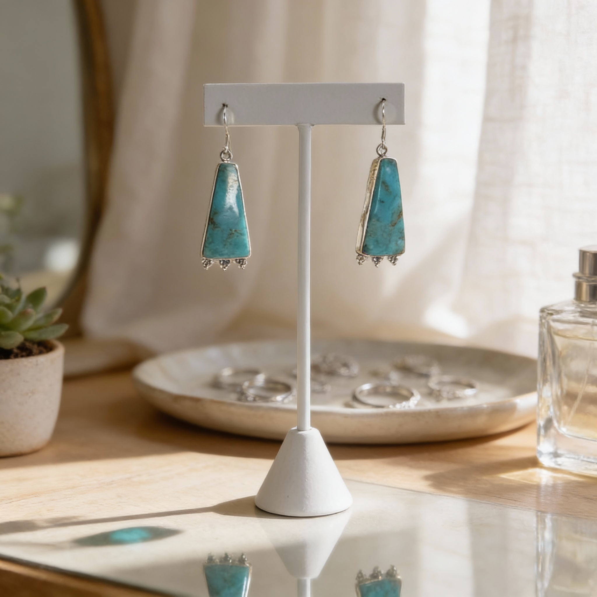 Sterling silver turquoise triangle earrings with natural stone veining on a minimalist display stand
