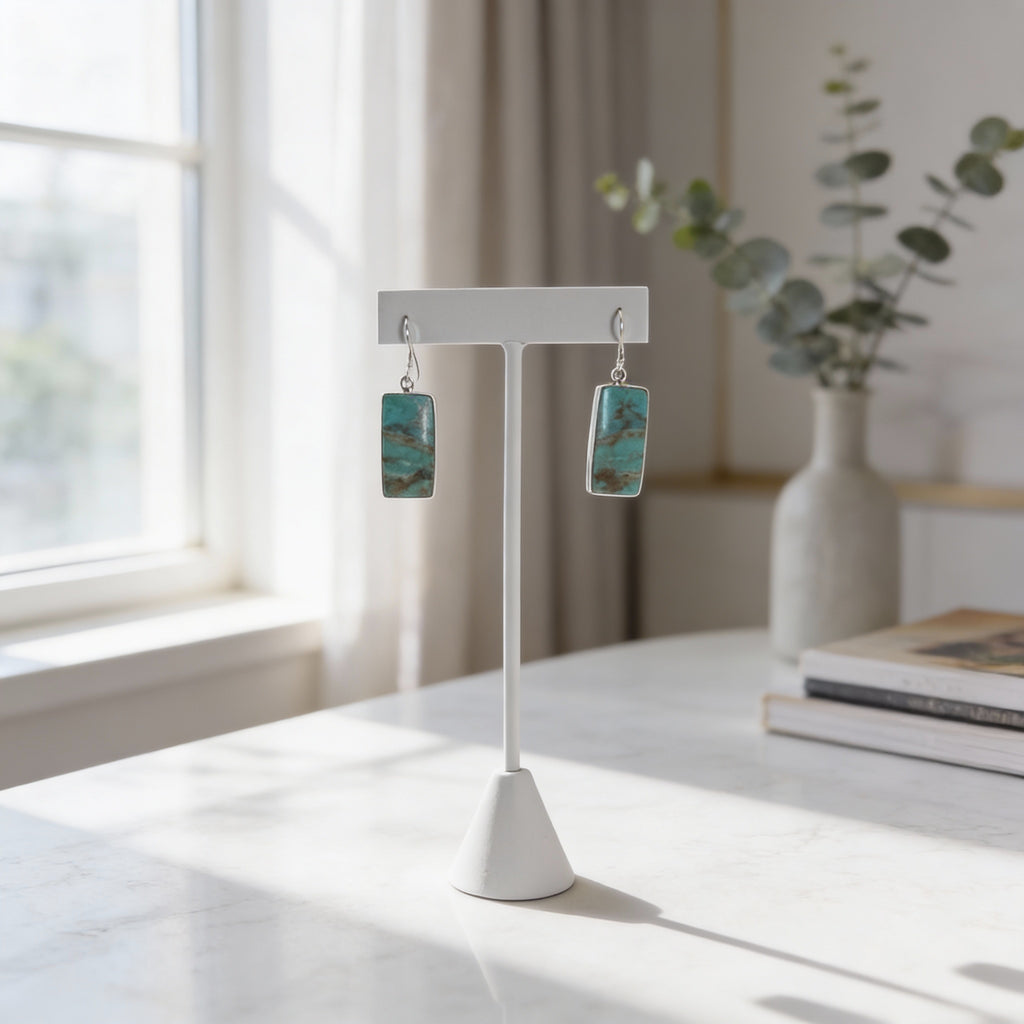 Sterling silver rectangular turquoise dangle earrings displayed on a minimalist white stand.