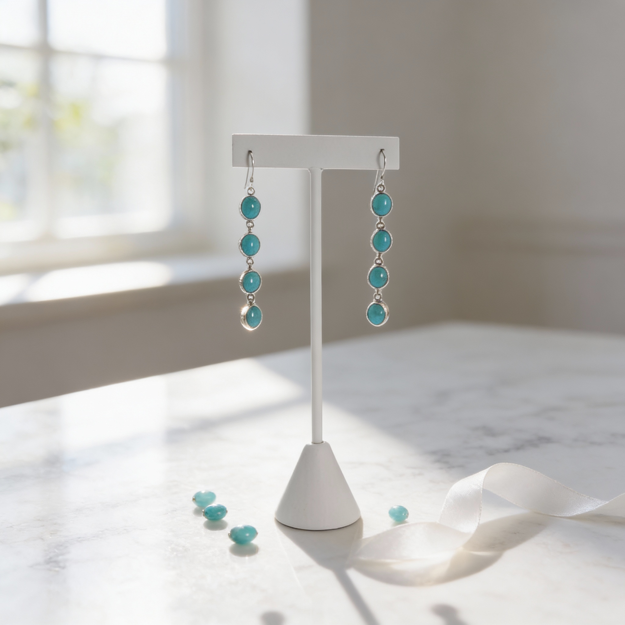 Sterling silver turquoise drop earrings with oval stones displayed on a jewelry stand