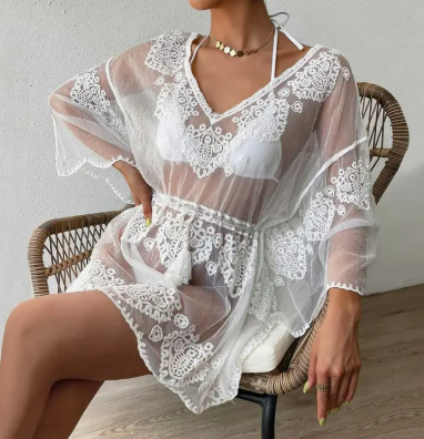 White embroidered lace beach cover-up with flowy sleeves and sheer back, worn over a swimsuit